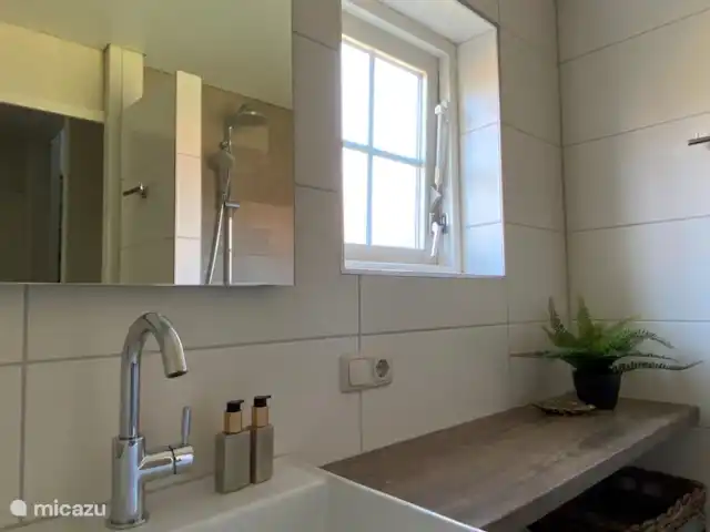 Badkamer met vloerverwarming, regendouche en wastafel op de begane grond.